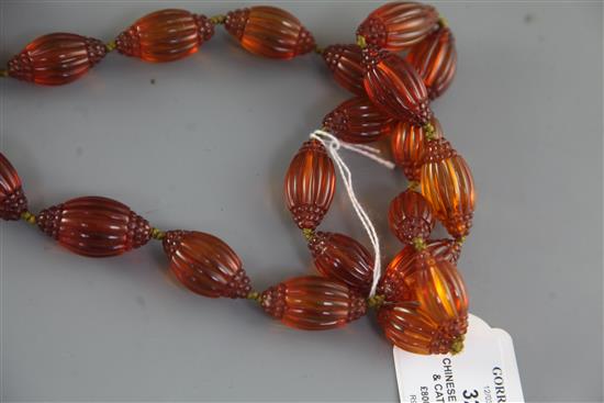 A Chinese amber necklace overall 66in.. sold with a copy of the catalogue